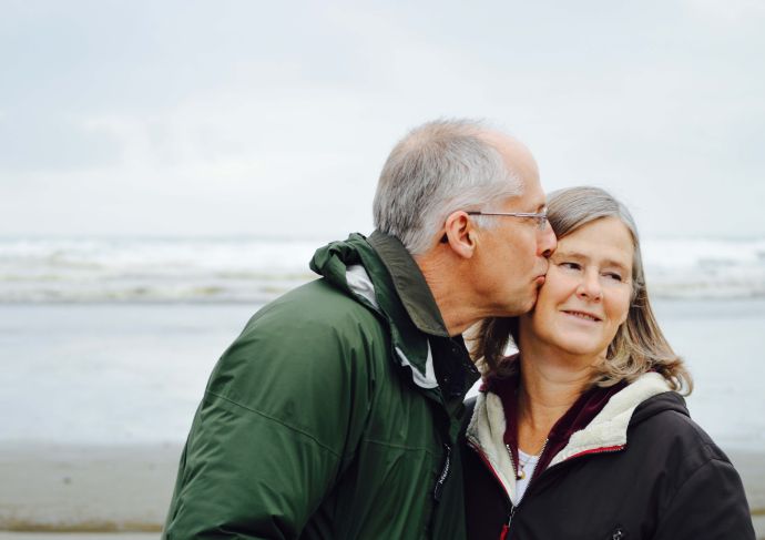Older man kissing his wife at the beach