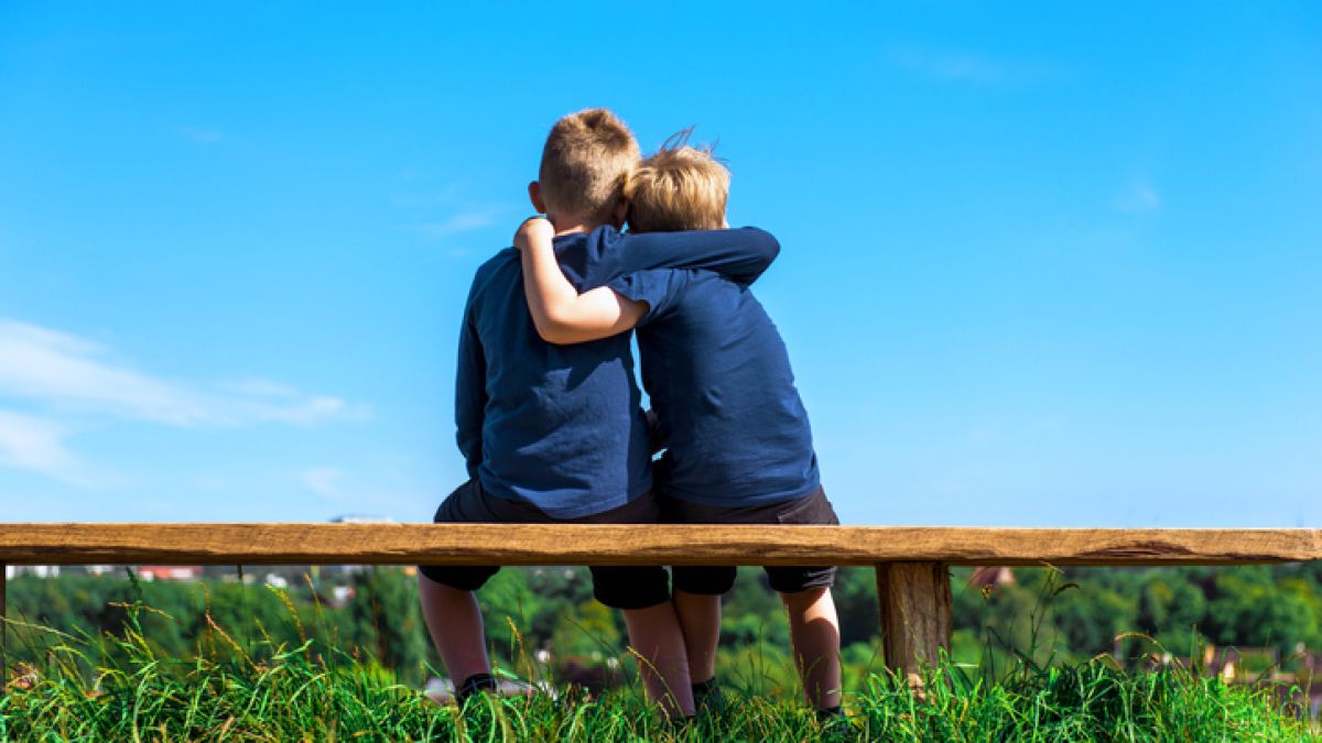 Children seated on bench hugging