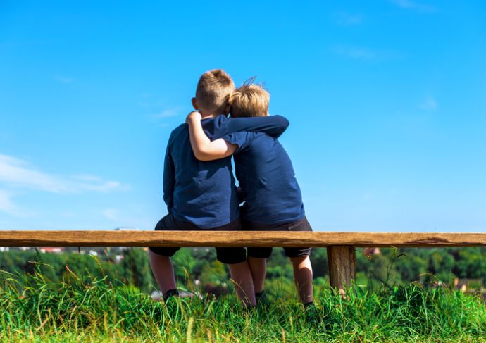 Children seated on bench hugging