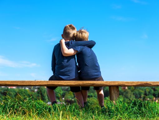 Children seated on bench hugging