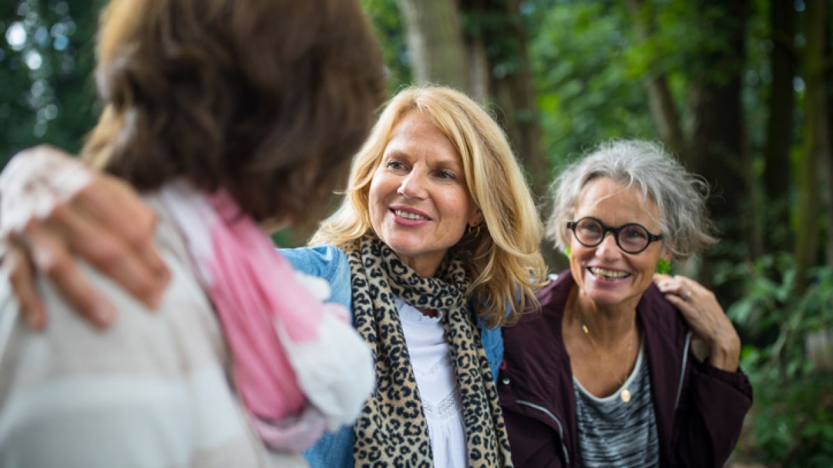 three older women hugging outside