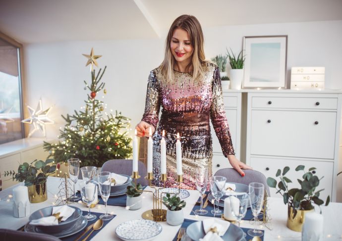 Woman lighting candles at a holiday dinner table