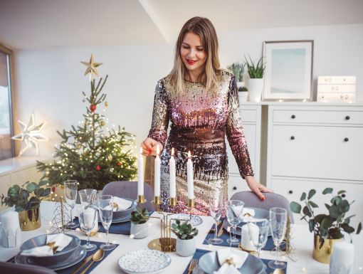 Woman lighting candles at a holiday dinner table