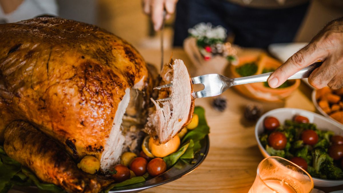 Person carving a turkey at the table