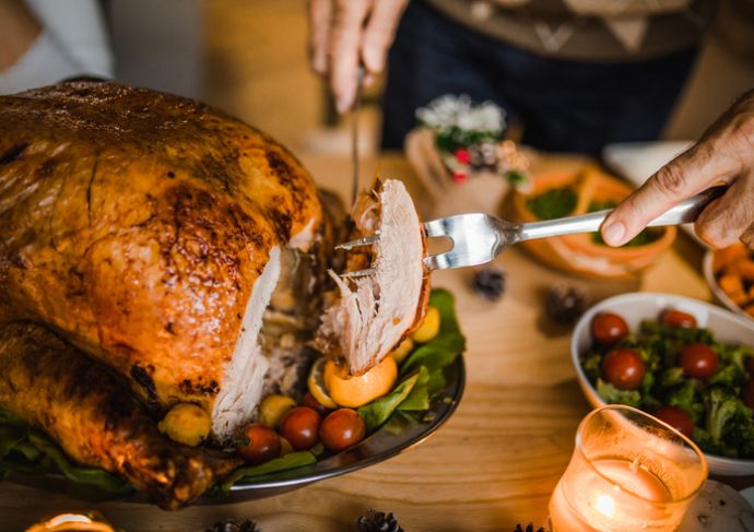 Person carving a turkey at the table