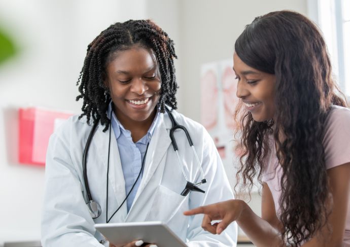 Black female doctor with young Black female patient