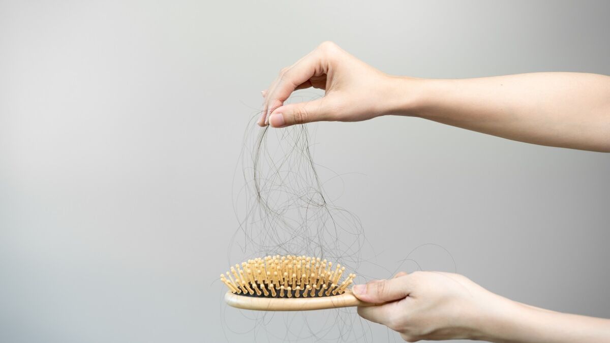 hands pulling dark hair from hair brush