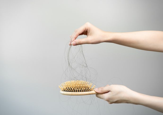 hands pulling dark hair from hair brush