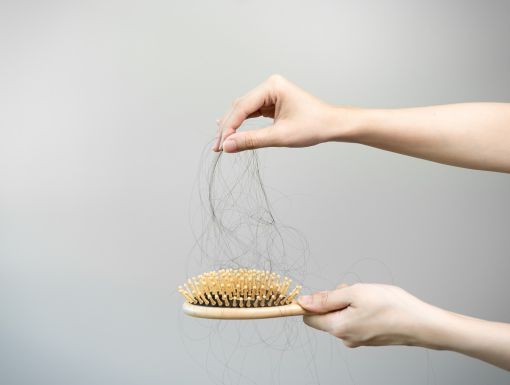 hands pulling dark hair from hair brush