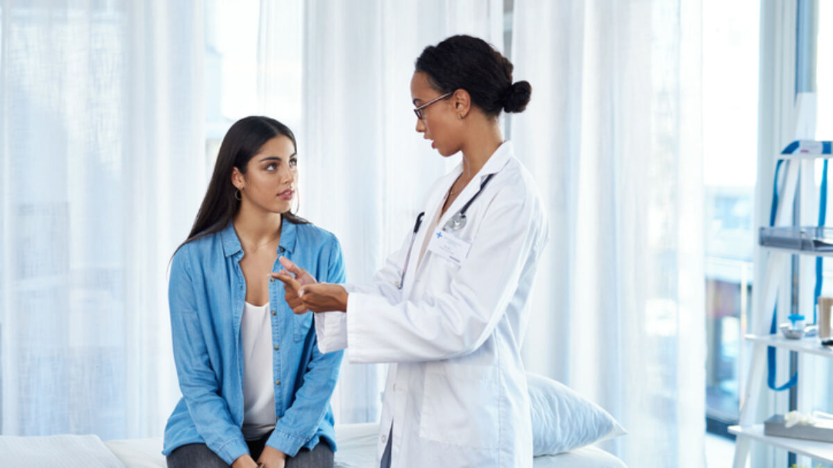Woman sitting in an exam room talking to her doctor