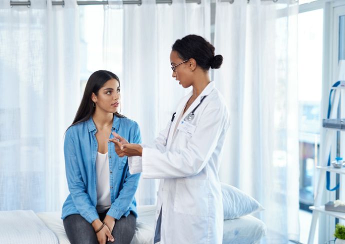 Woman sitting in an exam room talking to her doctor