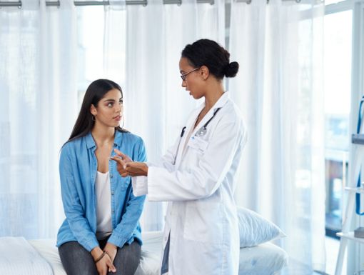 Woman sitting in an exam room talking to her doctor
