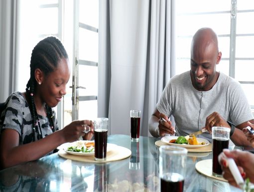 Black daughter and father eating lunch together at the dining table