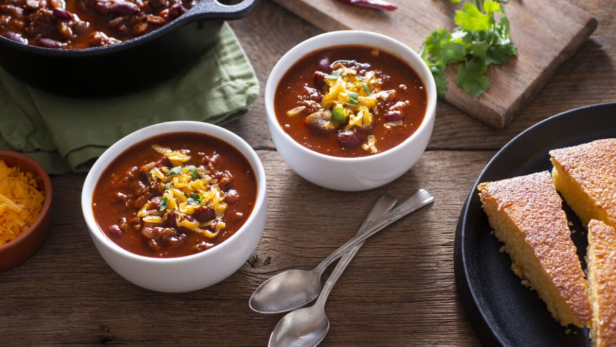 two bowls of chili with spoons on table