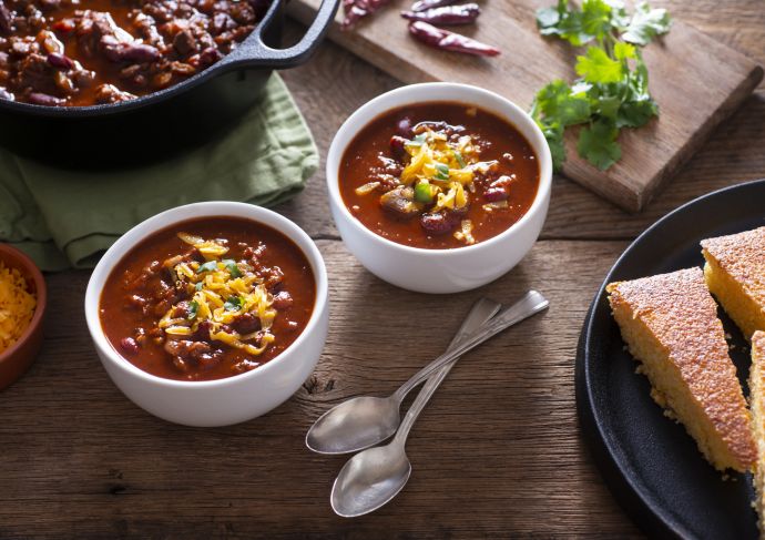 two bowls of chili with spoons on table