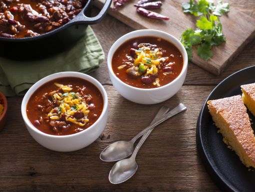 two bowls of chili with spoons on table