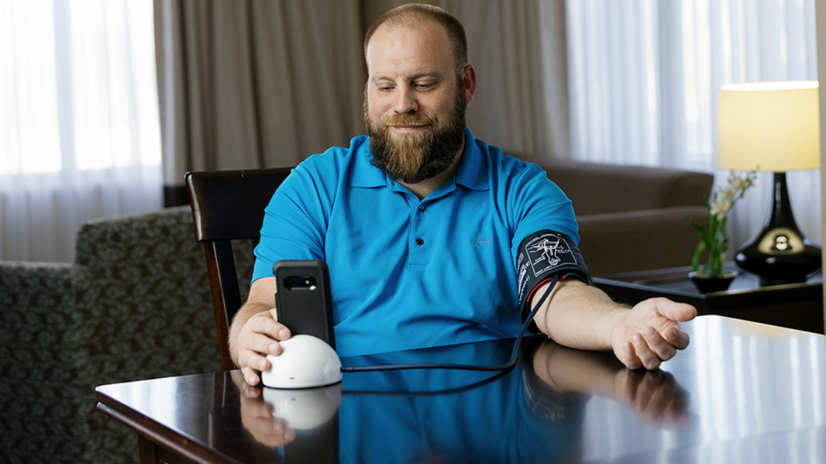 Man sitting at table checking his blood pressure