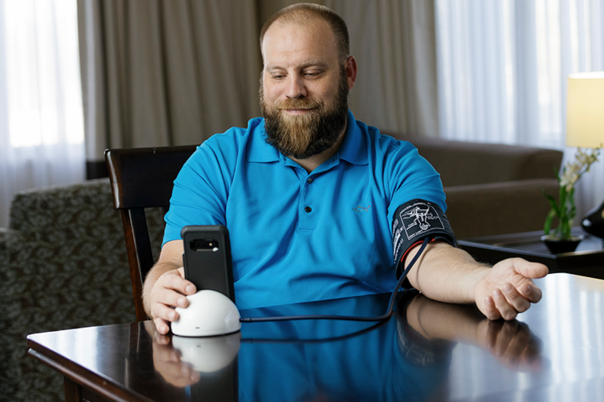 Man sitting at table checking his blood pressure
