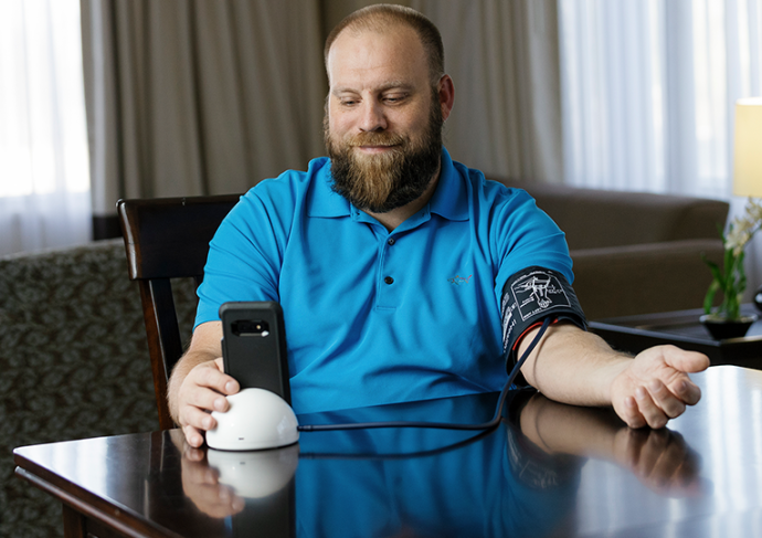 Man sitting at table checking his blood pressure