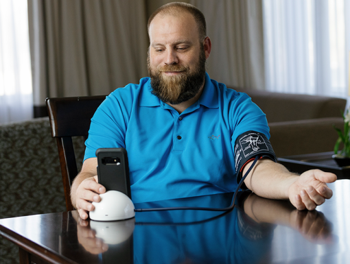 Man sitting at table checking his blood pressure