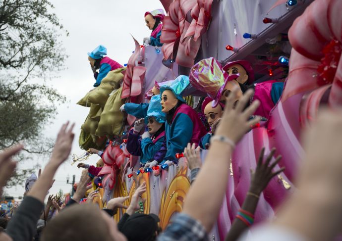 children and parents reaching for throws at a Mardi Gras parade