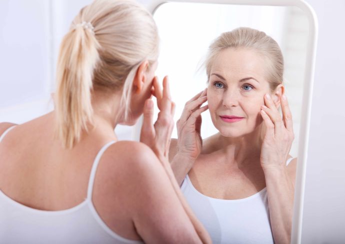 Older woman looking at skin in mirror after receiving Halo laser treatment