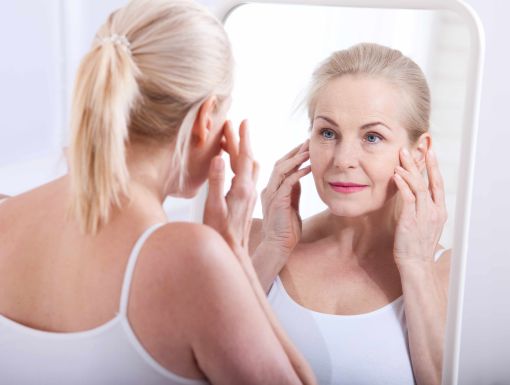 Older woman looking at skin in mirror after receiving Halo laser treatment