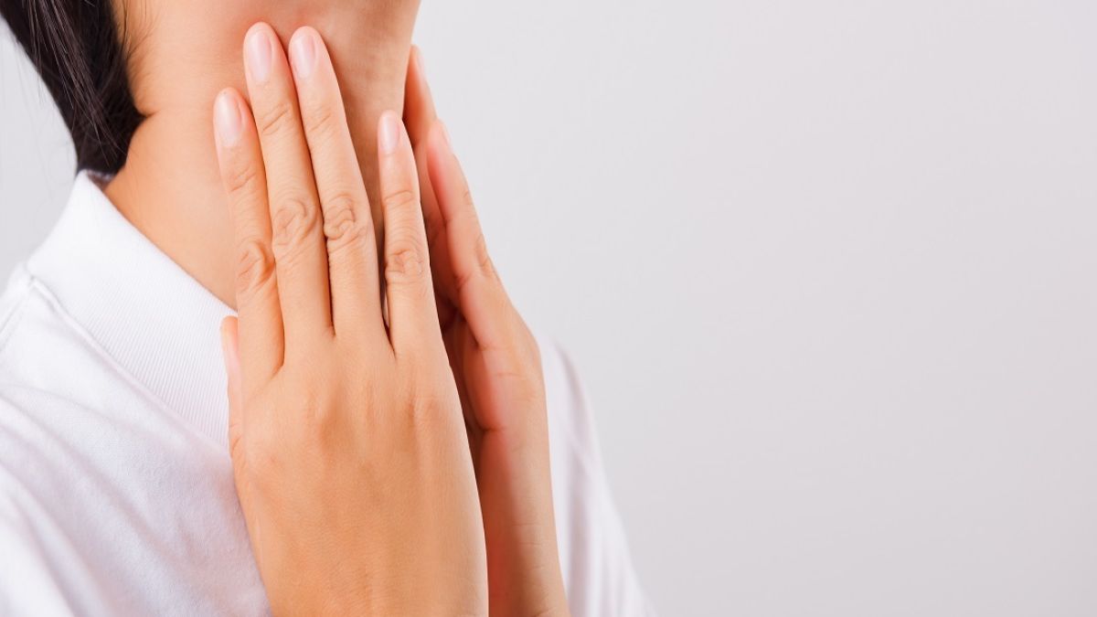 Asian woman experiencing discomfort gently touching her neck with concern
