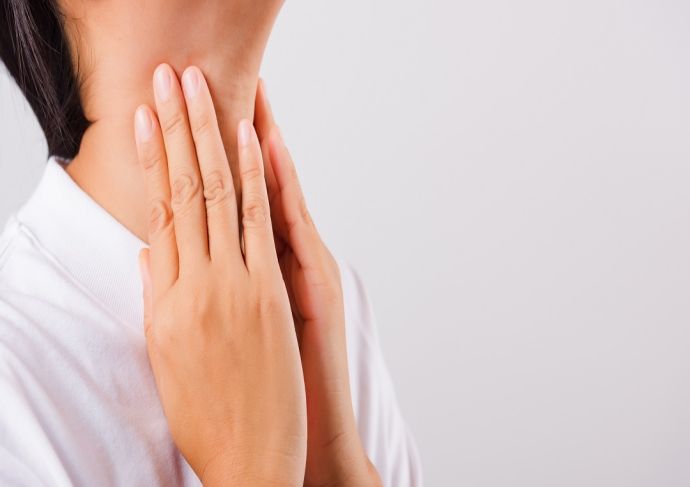 Asian woman experiencing discomfort gently touching her neck with concern