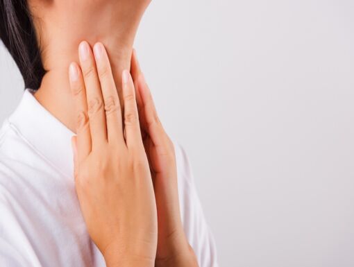 Asian woman experiencing discomfort gently touching her neck with concern