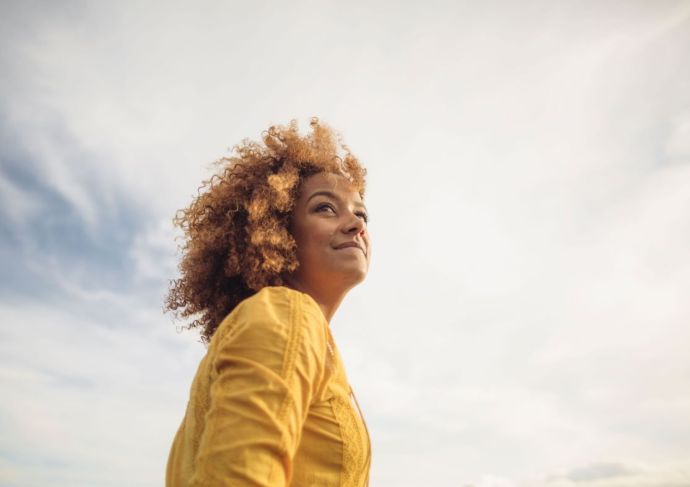 Woman looking into distance against cloudy sky