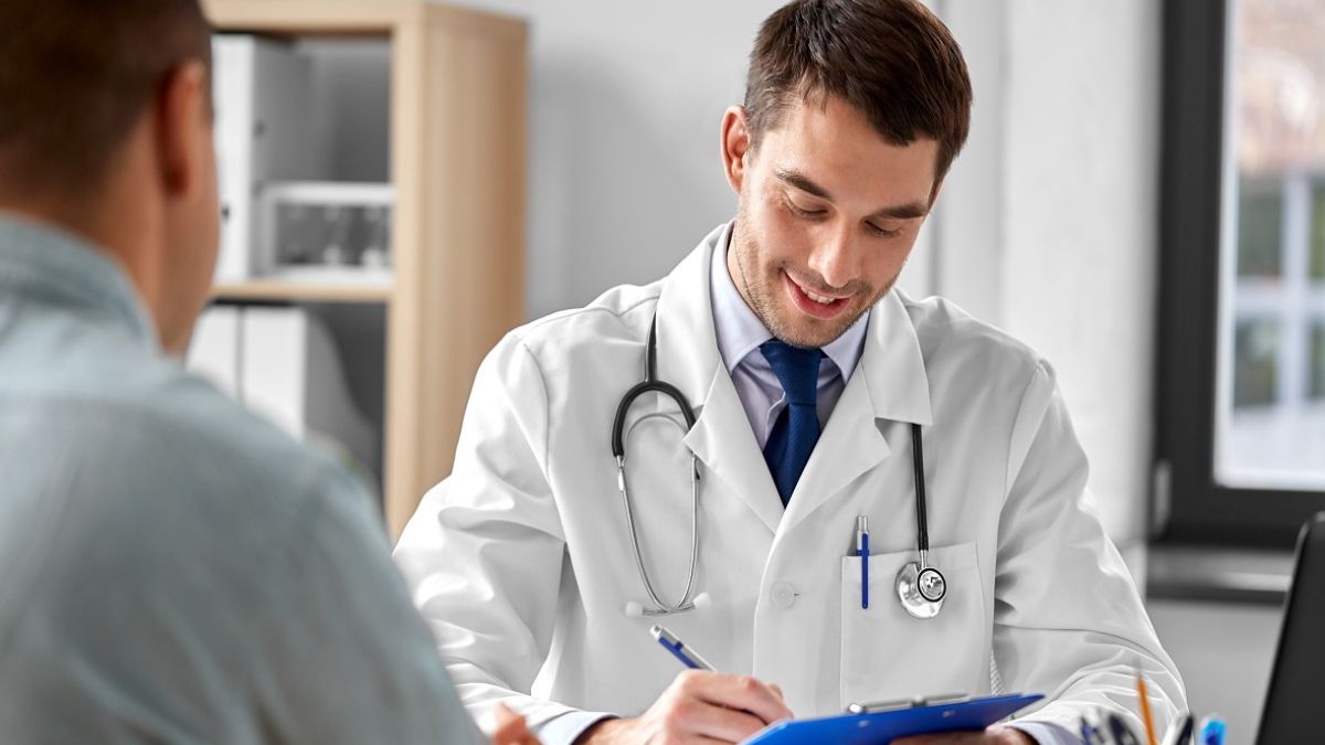Doctor with clipboard talking to male patient at medical office in hospital