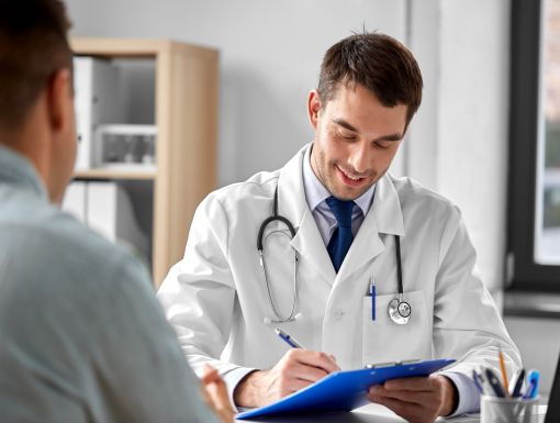 Doctor with clipboard talking to male patient at medical office in hospital