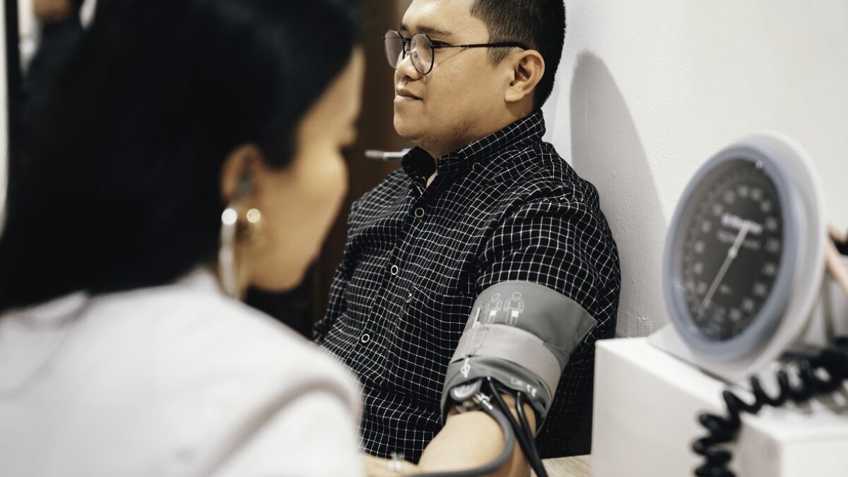 Man in clinic having blood pressure checked by female doctor