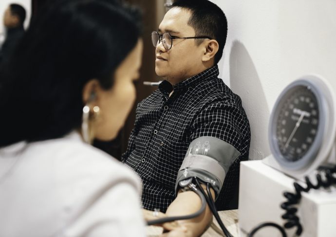 Man in clinic having blood pressure checked by female doctor