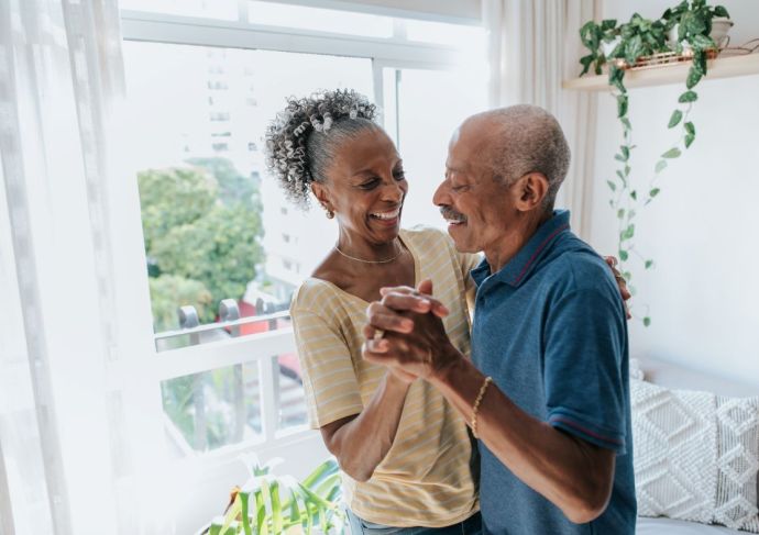 Senior couple dancing by window living room
