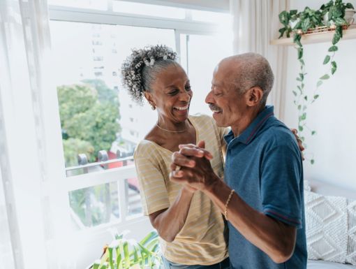 Senior couple dancing by window living room