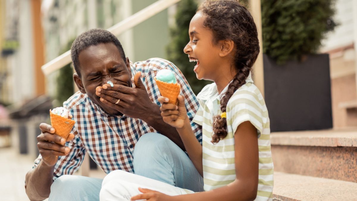 Young girl eating ice cream with her dad outside