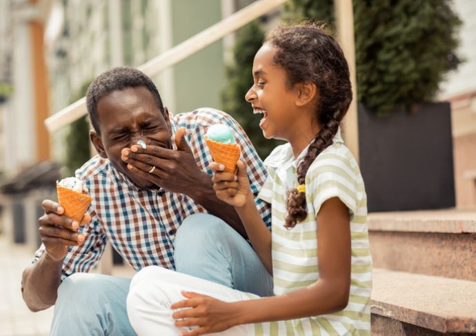 Young girl eating ice cream with her dad outside