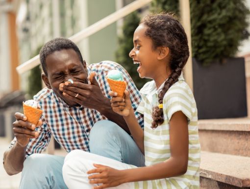 Young girl eating ice cream with her dad outside
