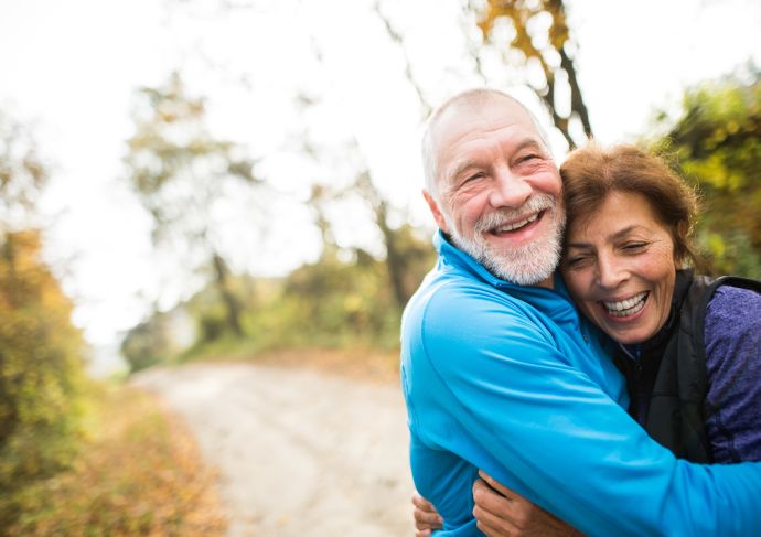 A man and woman walking together outdoors and hugging.