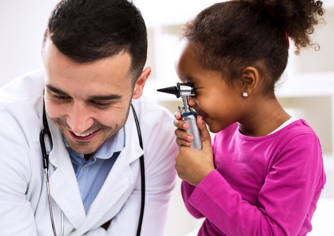 Young girl looking in doctors ear