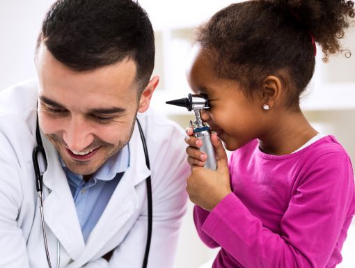 Young girl looking in doctors ear