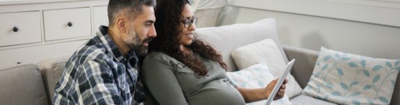 Pregnant mother and father sitting with tablet