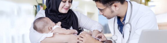 Mother holding baby while doctor gives shot