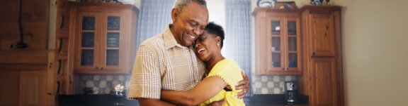 Elder man and woman hugging at home