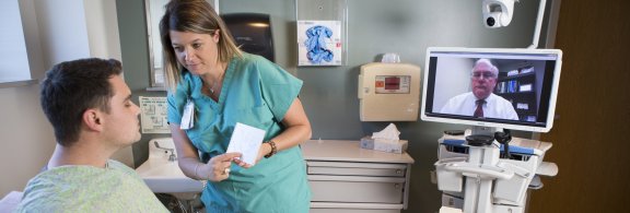 nurse assisting patient while doctor attends virtually
