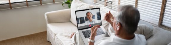 Elder man talking with doctor virtually on laptop