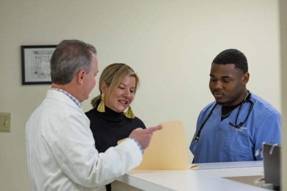 doctor with manila folder talks with patient and nurse