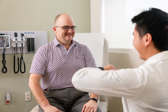 Dr. Yu and male patient smiling in exam room